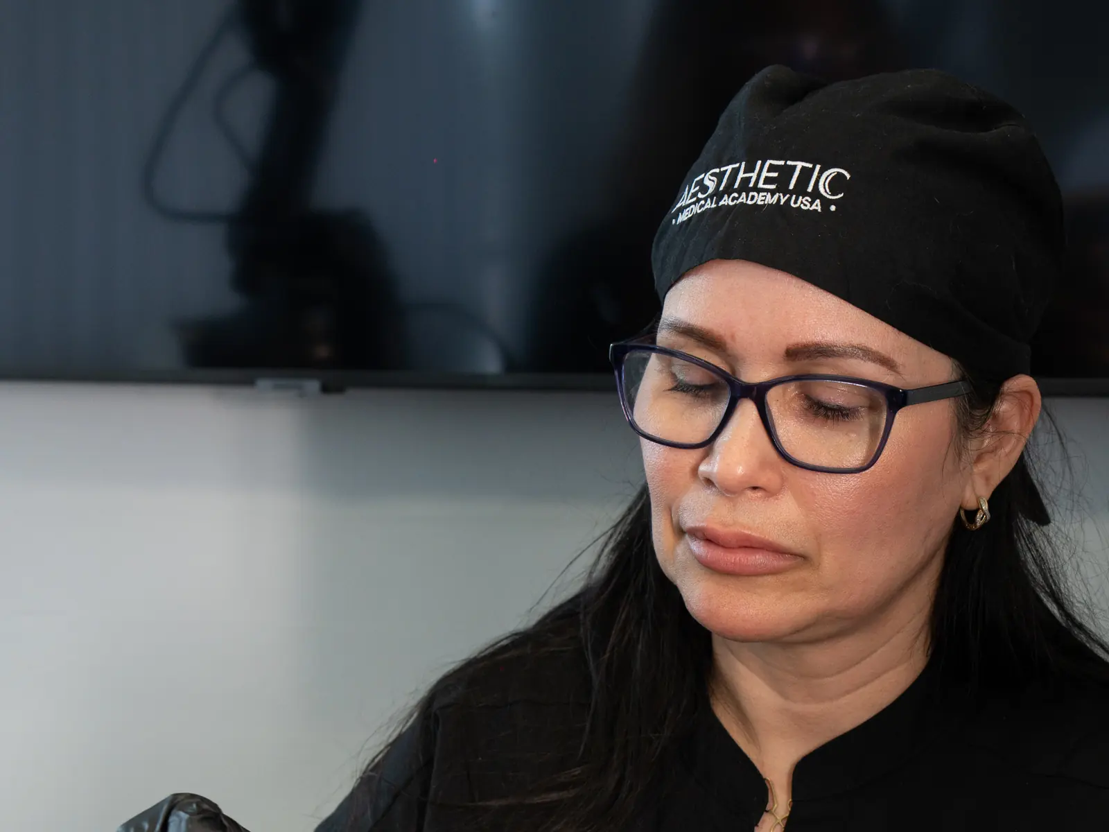 Instructora con gorro con el logo, mirando su trabajo en una clase de medicina estética