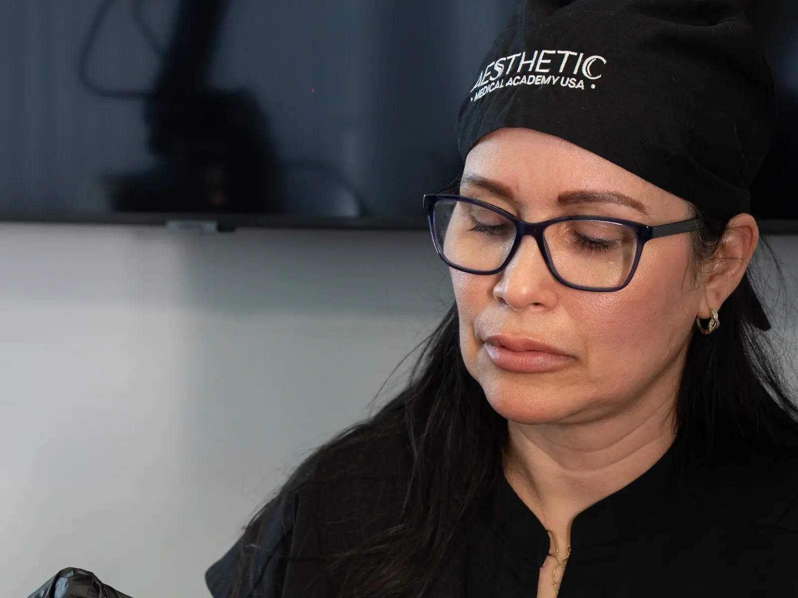 Instructora con gorro con el logo de la academia, concentrada durante una clase de inyectables