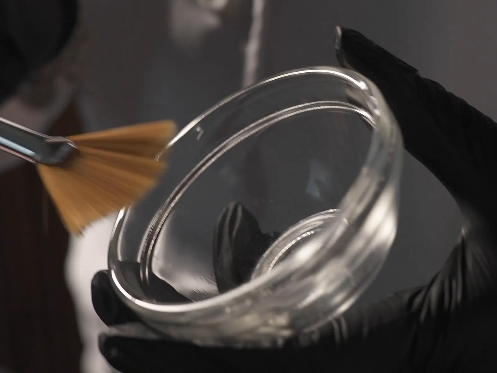 Bowl y pincel en manos con guantes negros, en clase de peeling
