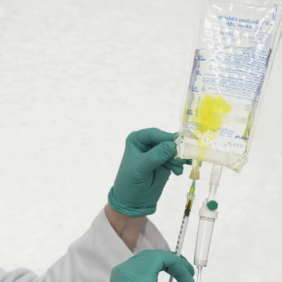 Manos con guantes preparando una bolsa de suero