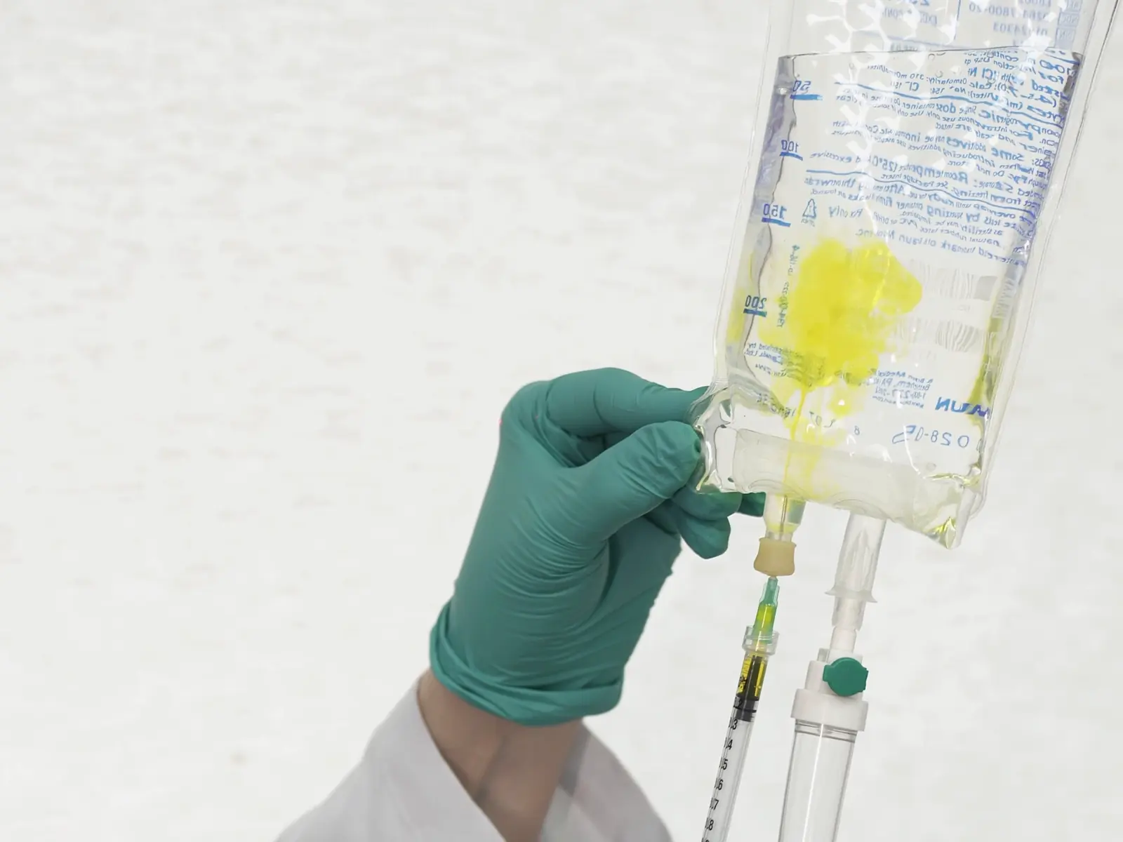 Manos con guantes preparando una bolsa de suero