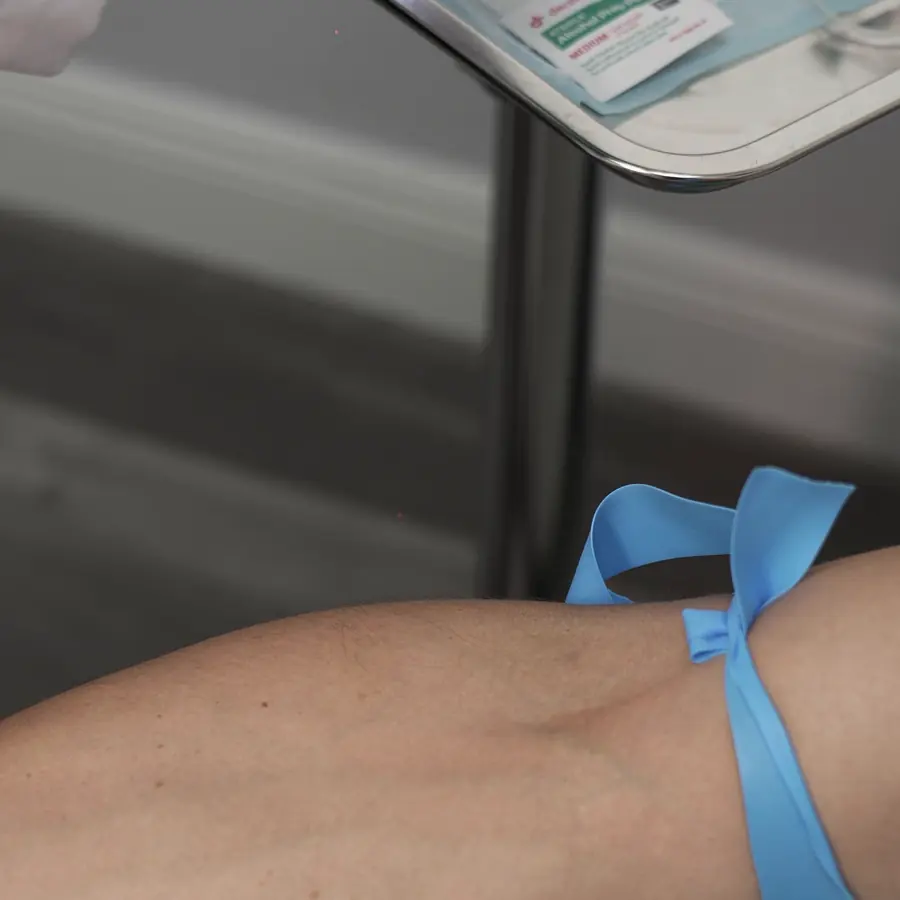 Torniquete en el brazo de un modelo real, manos con guantes, en clase de acceso venoso